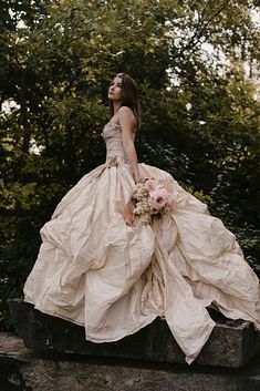 a woman in a wedding dress sitting on a rock