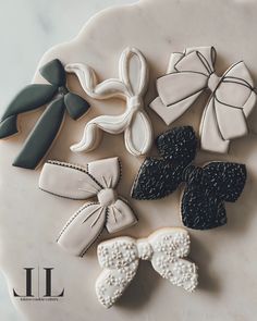 decorated cookies sitting on top of a white plate with black bows and bowknots