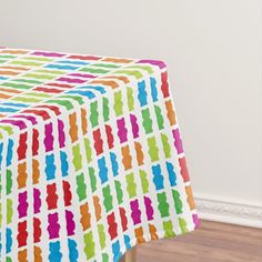 a colorful table cloth on top of a wooden table with white walls in the background