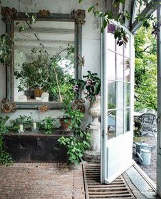 a mirror sitting on the side of a building next to potted plants in front of it