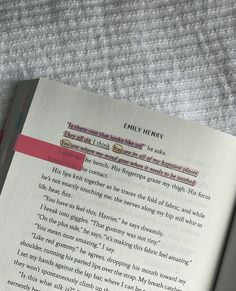 an open book sitting on top of a bed next to a pink and white pillow