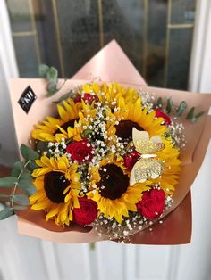 a bouquet of sunflowers and red roses in front of a door with a butterfly on it