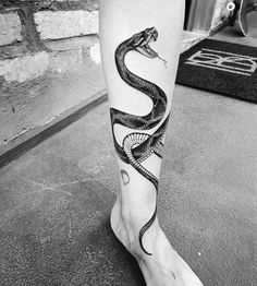 a black and white photo of a person's leg with a snake tattoo on it