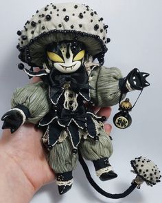 a hand holding a small doll with black and white decorations