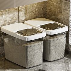 two trash cans sitting next to each other in front of a marble tiled wall and floor