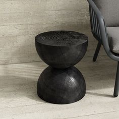 a chair and table sitting next to each other in a room with cement walls, concrete flooring and white tiles on the wall