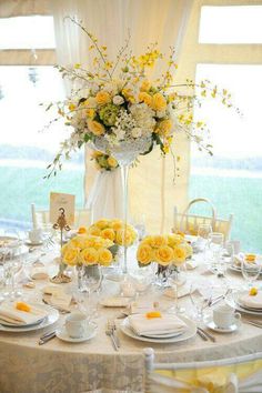 the table is set with yellow and white flowers