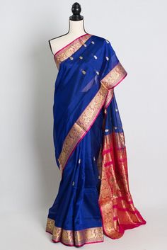 Add a touch of elegance to your wardrobe with this stunning Pattu Silk Cotton Saree in shades of blue and rani. Handcrafted with intricate detailing and exquisite craftsmanship, this saree exudes timeless beauty and sophistication. The contrasting blouse comes stitched and ready to wear, making it a hassle-free choice for any occasion. The soft and breathable fabric ensures comfort throughout the day, while the rich colors and luxurious texture make it a standout piece for any event. Whether you're attending a wedding, festival, or special gathering, this saree is sure to make you feel like a true Indian fashionista. Ready Stitched 38 Size with short sleeves Blouse which can be adjusted to size 40 and 42. Color : Blue and Rani. Blouse Piece : Yes. Fall Pico : Yes.  Care: Dry-Clean Only. Festive Blue Chanderi Blouse Piece, Elegant Blue Blouse Piece With Cutdana, Elegant Blue Blouse Piece For Navratri, Elegant Blue Blouse For Navratri, Elegant Blue Cotton Silk Blouse Piece, Blue Bollywood Blouse Piece With Self Design, Blue Self-design Blouse Piece For Navratri, Blue Self Design Blouse Piece For Festivals, Bollywood Style Blue Self-design Blouse Piece