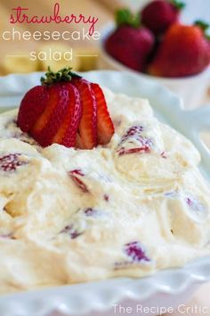 strawberry cheesecake salad on a white plate with strawberries in the bowl behind it