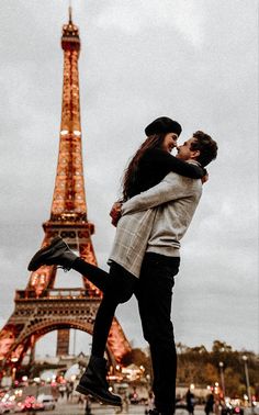 a man and woman standing in front of the eiffel tower with their arms around each other