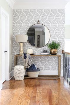 a room with a mirror, lamp and vase on the table in front of it