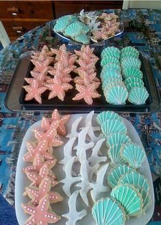 three trays filled with decorated cookies on top of a table