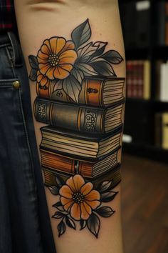 a person with a tattoo on their arm holding a stack of books and yellow flowers