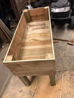 a wooden bed frame sitting on top of a floor next to a parked car in a garage