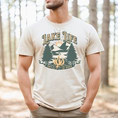 Our retro and stylish Lake Life tshirt is perfect for those summer vacations at the lake. Whether you are lounging around on the beach at your cabin or cottage, or enjoying some quiet time paddle boarding on the lake, this tshirt will keep you cool and comfortable. The simple mountain, campfire and pine tree design is perfect for camping and hiking in the Rockies. It makes a great gift for outdoor enthusiasts or anyone that wants to relive days at the lake. Made with lightweight and breathable fabric, this tshirt ensures comfort even in warm climates. The sleeveless design allows for easy movement and keeps you cool as you embark on your summer adventures. High quality print makes it an ultimate statement shirt for years to come. This item has side seams to provide structural support. All Outdoor Short Sleeve T-shirt For Summer, Outdoor Short Sleeve T-shirt With Front Print, Summer Outdoor Cotton T-shirt, Outdoor Summer T-shirt With Screen Print, Summer Outdoor Screen Print T-shirt, Screen Print T-shirt For Summer Outdoor, Casual T-shirt For Outdoor Summer Activities, Casual Summer T-shirt For Outdoor, Casual Short Sleeve T-shirt For Adventure