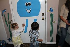 two young children standing in front of a door with an elephant painted on the side