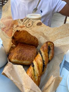 some pastries are sitting in a basket on a table with a cup of coffee