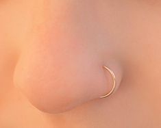 a close up view of the back of a woman's breast with a crescent shaped nose ring