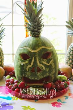 a watermelon carved to look like a face with fruit around it on a table