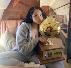 a woman sitting on the back of an airplane holding up a basketball in front of her face