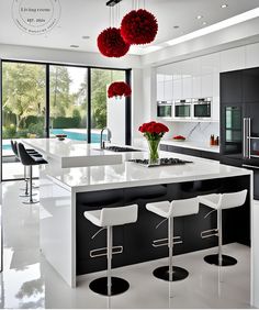 a modern kitchen with white counter tops and black cabinets, red flowers in vases on the island