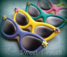 three decorated sunglasses sitting on top of a blue and green tablecloth with the words sweet - cakes written below them