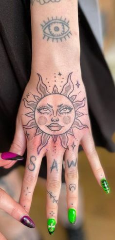 a woman's hand with sun and moon tattoos on it, while she has green fingernails