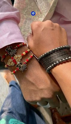 two people wearing bracelets holding each other's hands