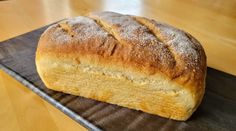 a loaf of bread sitting on top of a metal tray next to a wooden table