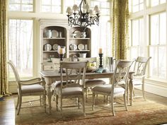 a dining room table with chairs and a chandelier hanging from the ceiling in front of windows