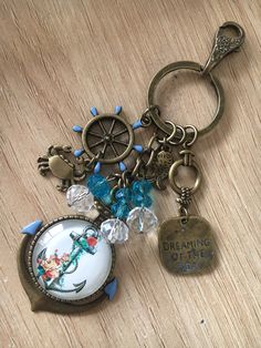 a keychain with charms on it sitting on top of a wooden table next to a bottle opener