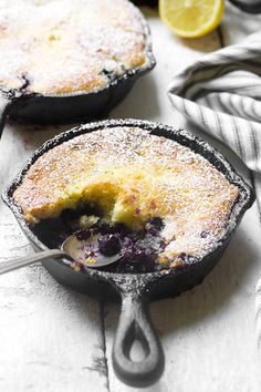 blueberry cobbler in a cast iron skillet with a spoon and lemon wedges