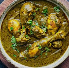 a bowl filled with chicken curry and garnished with parsley on the side