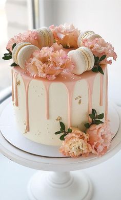 a white cake with pink flowers and macaroni shells on top