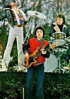 the rolling stones performing on stage in front of drummers and drums, with one man holding