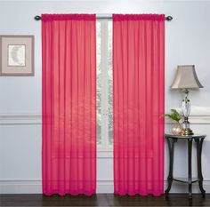 pink sheer curtains hanging in front of a window with a lamp on the side table