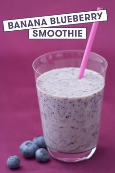 a banana blueberry smoothie in a glass with a pink straw and some blueberries