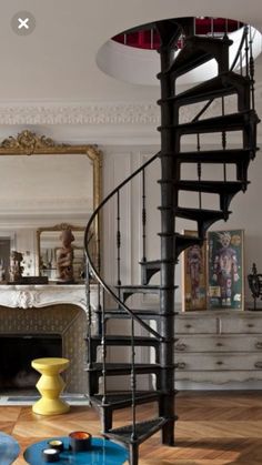 a living room filled with furniture and a spiral staircase in front of a fire place