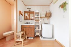 a small bathroom with wood floors and white walls, including a toilet, sink, and shelving unit