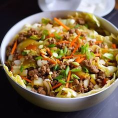 a white bowl filled with meat and veggies on top of a black table