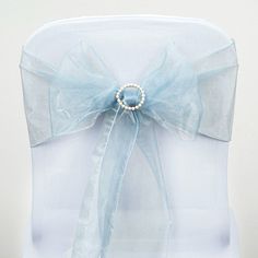 the back of a chair with a blue bow and pearl brooch attached to it