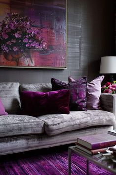 a living room filled with lots of furniture and purple pillows on top of a couch