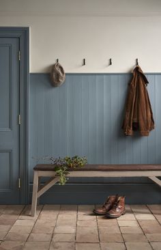 a wooden bench sitting under a coat rack next to a pair of shoes on the floor