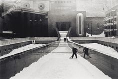 black and white photograph of two people standing in the middle of a snow covered walkway