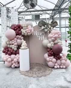 a large balloon arch with a cake and flowers on it in the middle of a room