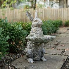 a statue of a rabbit holding a piece of paper in it's mouth sitting on a stone walkway