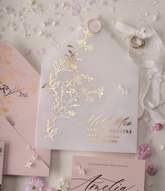 the wedding stationery is laid out with pink and gold flowers on it's side