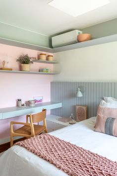 a bedroom with pink walls and white bedding, shelves on the wall, and a wooden chair at the foot of the bed