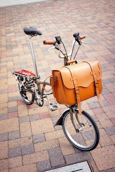 a bicycle with a saddle on the back parked in front of a brick sidewalk area