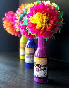 three bottles filled with colorful flowers on top of a wooden table next to each other